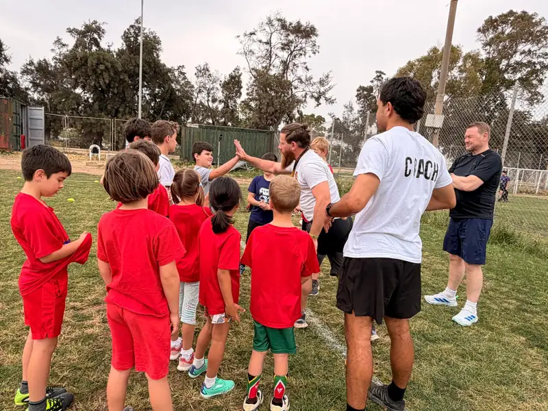Youth coach high-fiving a player during a team talk