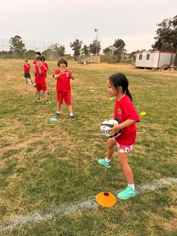 Young Stompers player holding a rugby ball during a drill