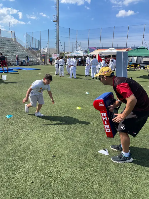 Child running at a tackle shield held by a coach